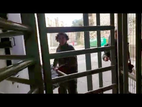Israeli settler threatens Palestinian kids with club in front of soldiers at checkpoint in Hebron
