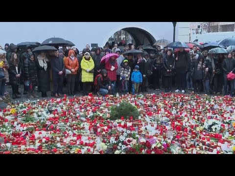 People hold a moment of silence to honour the victims of the Prague shooting